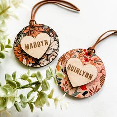 two personalized wooden tags with flowers and leaves on the side, one has a heart