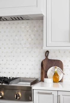 a stove top oven sitting next to a wooden cutting board and white cabinets in a kitchen