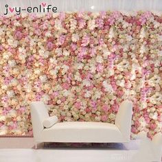 a white couch sitting in front of a flower wall with pink and white flowers on it