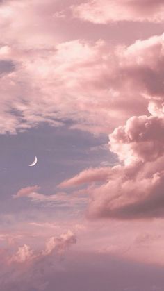 an airplane flying in the sky with clouds and a half moon above it at dusk