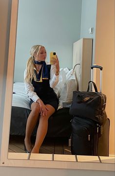 a woman sitting on a bed taking a selfie with her cell phone in front of the mirror