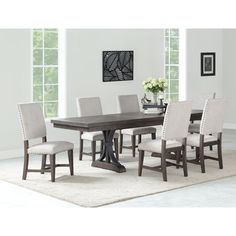 a dining room table with six chairs and a rug on the floor in front of it