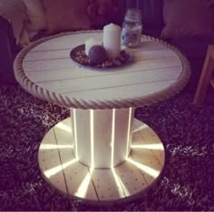 a table that has some lights on it in the middle of a living room with couches and pillows