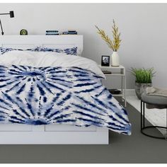 a bed with a blue and white comforter on top of it next to a night stand