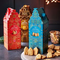 three different colored boxes with cookies in front of them on a table next to some lights