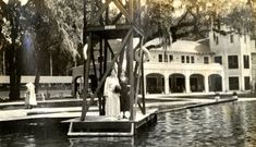 an old photo of a statue in front of a building with water and trees around it