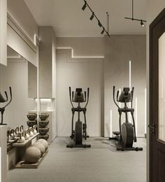 there are many exercise machines in the room with mirrors on the wall and lights hanging from the ceiling