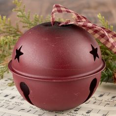 a red christmas ornament with black stars on it sitting on sheet music paper