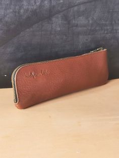 a brown leather pencil case sitting on top of a table