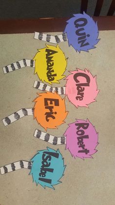 four different colored paper cutouts on the ground with words written in each one's own language