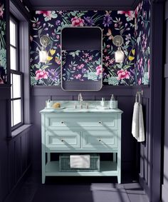 a bathroom with floral wallpaper and blue vanity in the corner, along with a large mirror