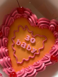 a cake in the shape of a heart with words on it and cherries around it