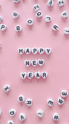 the words happy new year spelled out in small letters on a pink and white background