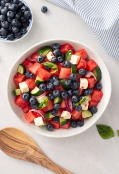 a bowl filled with watermelon, blueberries and cucumber