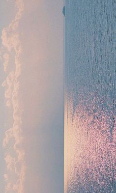 an airplane is flying over the ocean on a clear day with pink and blue colors