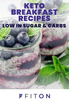 two jars filled with blueberries and yogurt on top of a white table