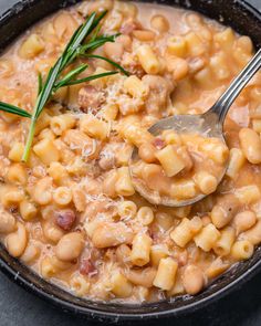 a bowl filled with macaroni and cheese on top of a black table next to a spoon