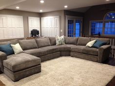 a large sectional couch sitting in a living room next to a rug on the floor