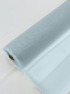 a roll of white sheer fabric sitting on top of a wooden table