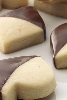 some cookies with chocolate icing on top of them sitting on a white plate next to each other