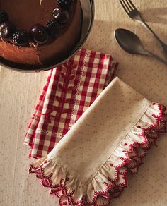 two napkins with ruffled edges sit next to a chocolate cake on a table