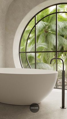 a white bath tub sitting in front of a window next to a palm leaf covered wall