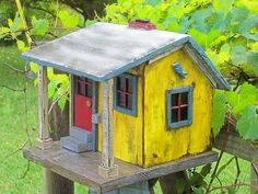 a yellow bird house sitting on top of a wooden fence