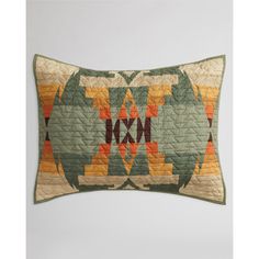 a green and orange quilted pillow sitting on top of a white wall