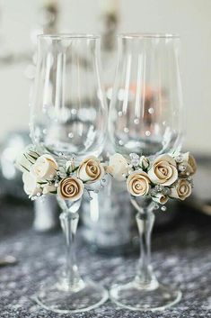 two wine glasses with flowers in them sitting on a table