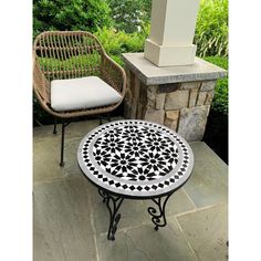 an outdoor table and chair sitting on a stone patio with grass in the back ground