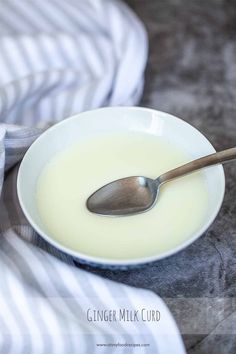 a white bowl filled with milk and a spoon on top of it next to a striped towel