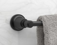 a black towel hanging on the side of a wall next to a toilet paper roll