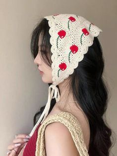 a woman wearing a white crochet hat with cherries on it's side