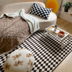 a living room with a checkered rug and white couch, coffee table on the floor