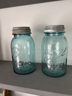 two blue mason jars sitting on top of a shelf