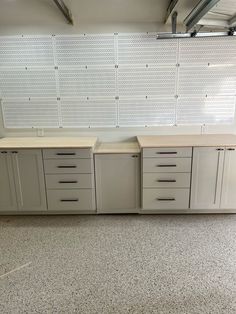 an empty garage with several drawers and cabinets on the wall, in front of white pegboard