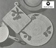 two crocheted placemats on top of a table next to a hat