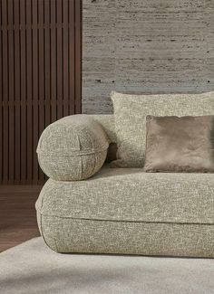 a couch with two pillows on top of it in front of a wooden paneled wall