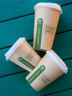 three coffee cups sitting next to each other on top of a green wooden table,