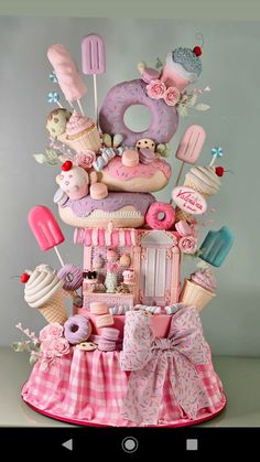 a pink cake with donuts, ice cream and candies on it's top