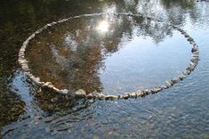 there is a circle made out of rocks in the middle of some water with sun shining on it