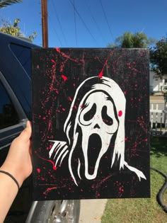 a person holding up a painting of a screamy ghost