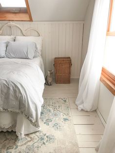 a bedroom with a bed, rug and window in the corner on the floor next to it