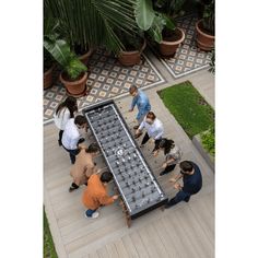 a group of people standing around a giant checker board on the ground next to potted plants