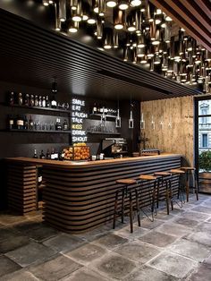 an image of a bar with stools and lights hanging from the ceiling above it