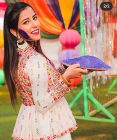 a woman holding a plate in front of a colorful backdrop with balloons and streamers