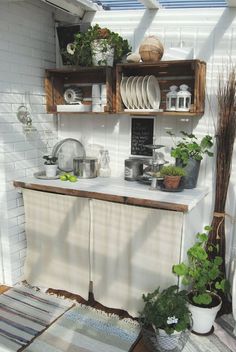 an outdoor kitchen with pots and pans on the shelves, potted plants and other items