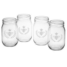 four glass jars with bee designs on the front and one has a crown in the middle