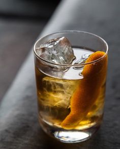 an orange peel sitting on top of a glass filled with liquid and ice cubes