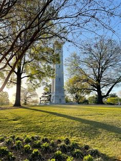 a tall white clock tower sitting in the middle of a park next to some trees